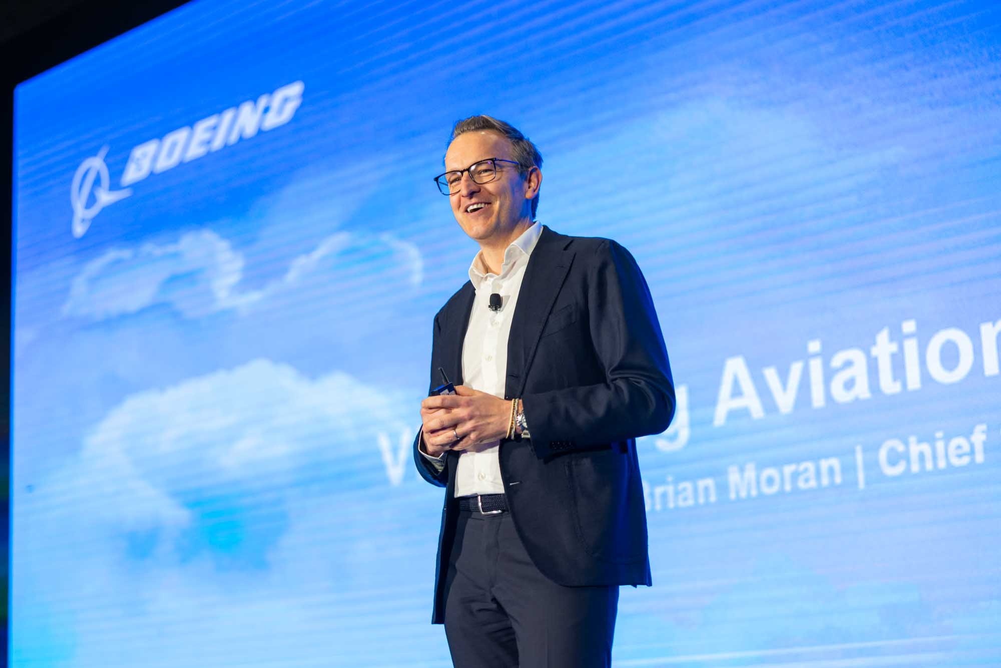 A presenter smiling on stage