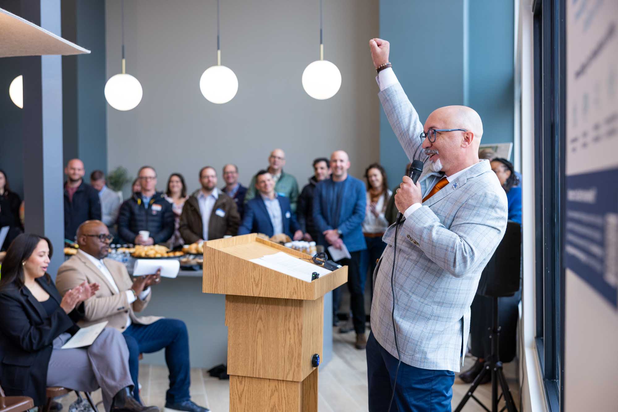 Speaker delivering a speech, smiling with hand raised