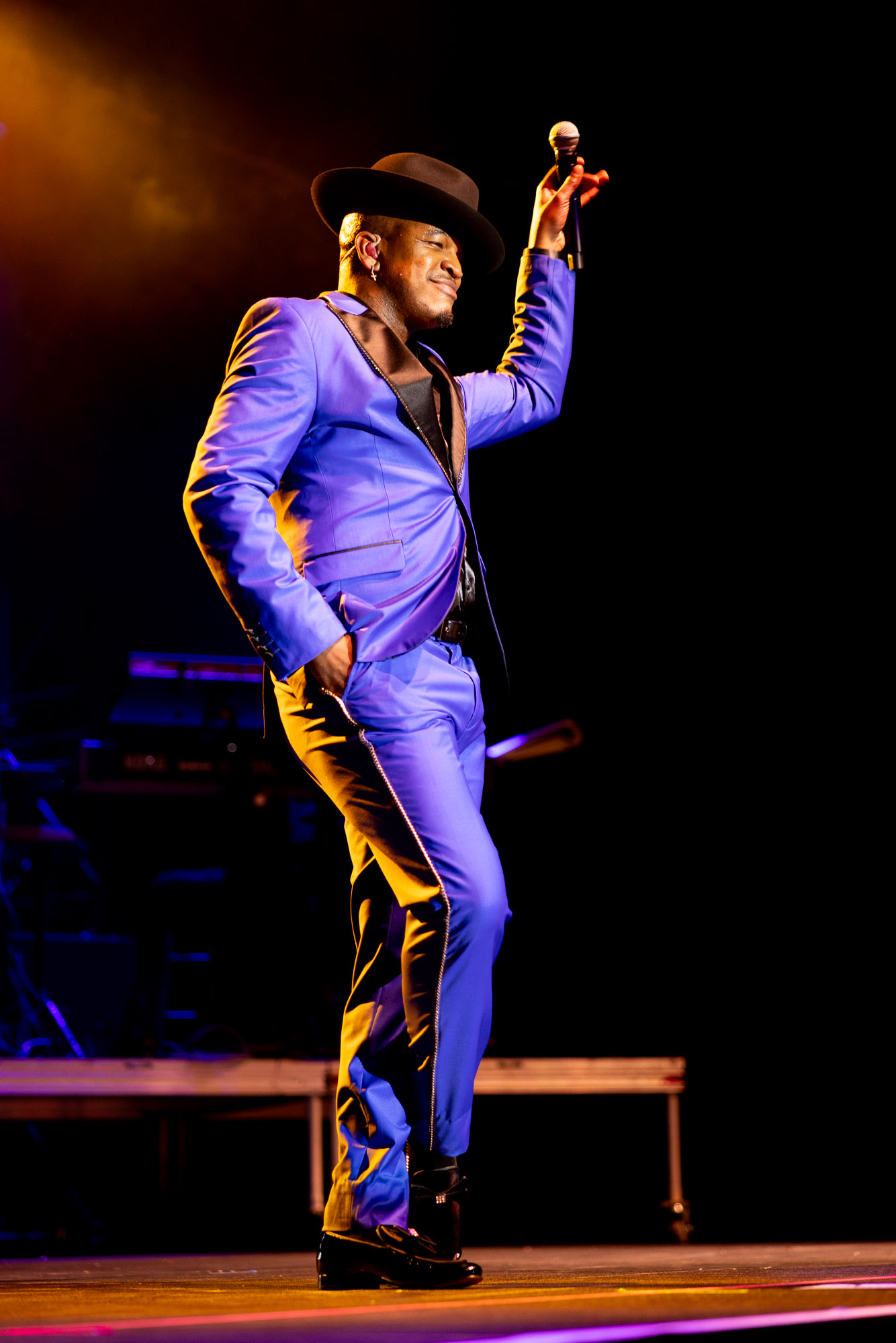 Performer on stage in blue suit holding microphone