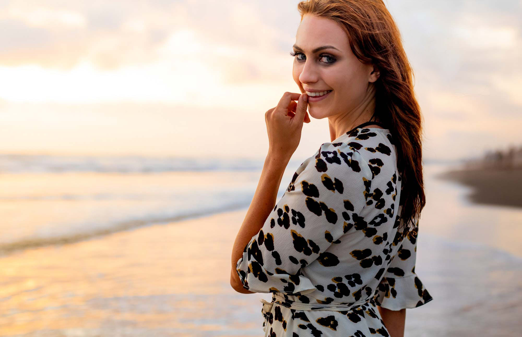Fashion lifestyle photography of a woman posing by the ocean during golden hour.