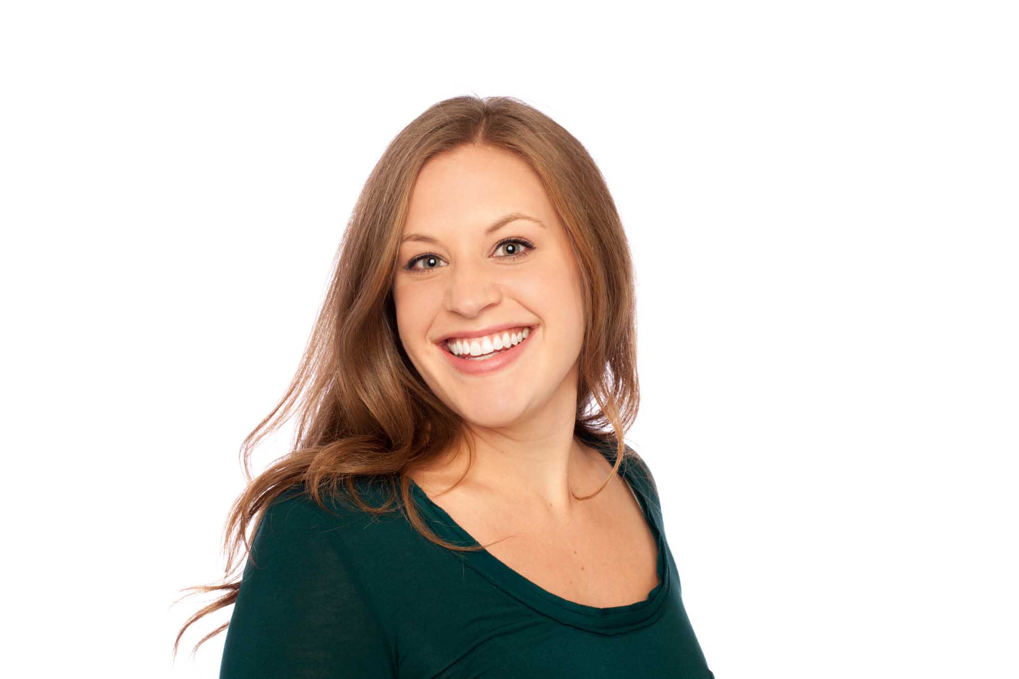 Studio headshot of Becca Manning on a white background — long auburn hair, bright laugh, forest-green scoop-neck top.