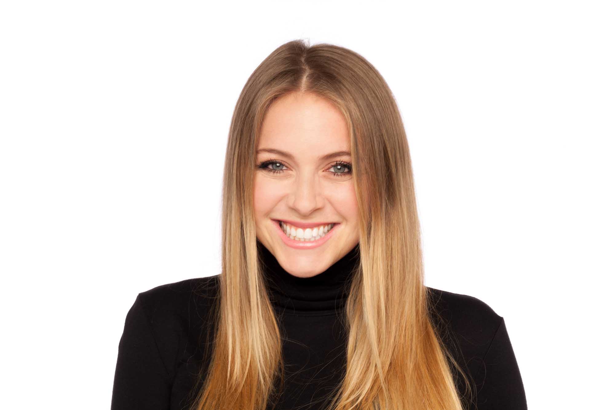Studio headshot of Jillian Pavsner on a white background — long blonde hair, bright smile, black turtleneck.