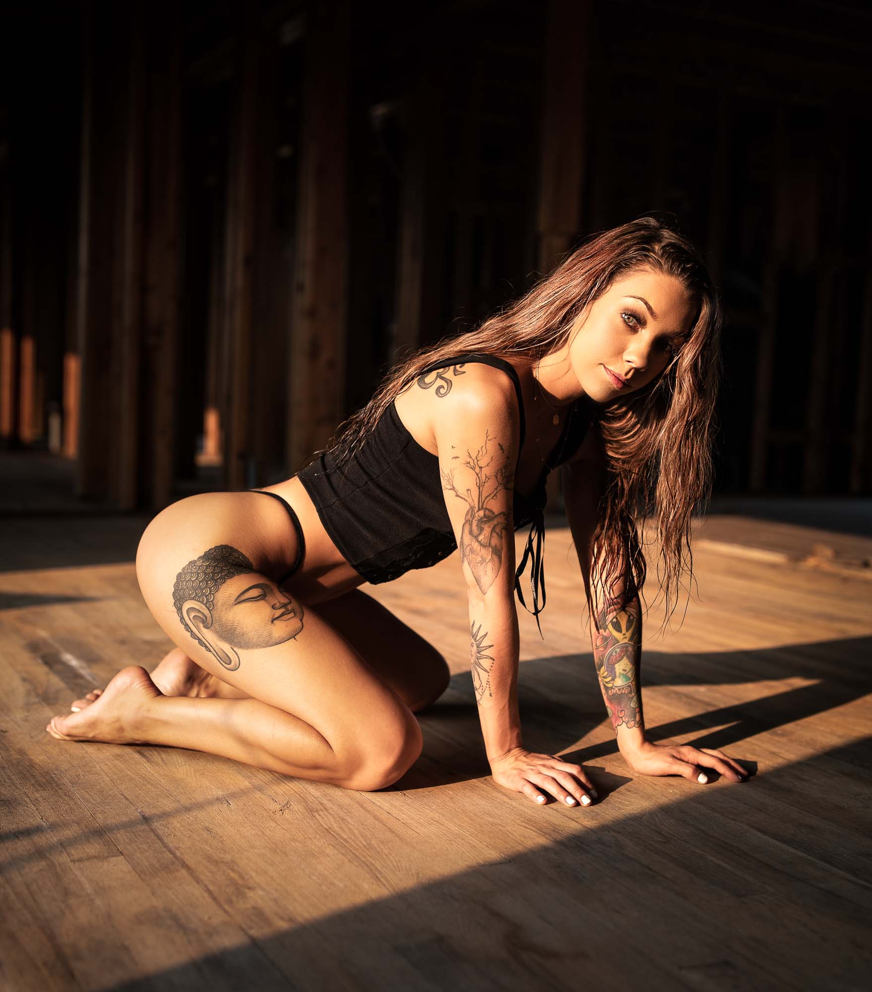 Lifestyle portrait of tattooed model @space.junkiee on a hardwood floor in dramatic warm lighting
