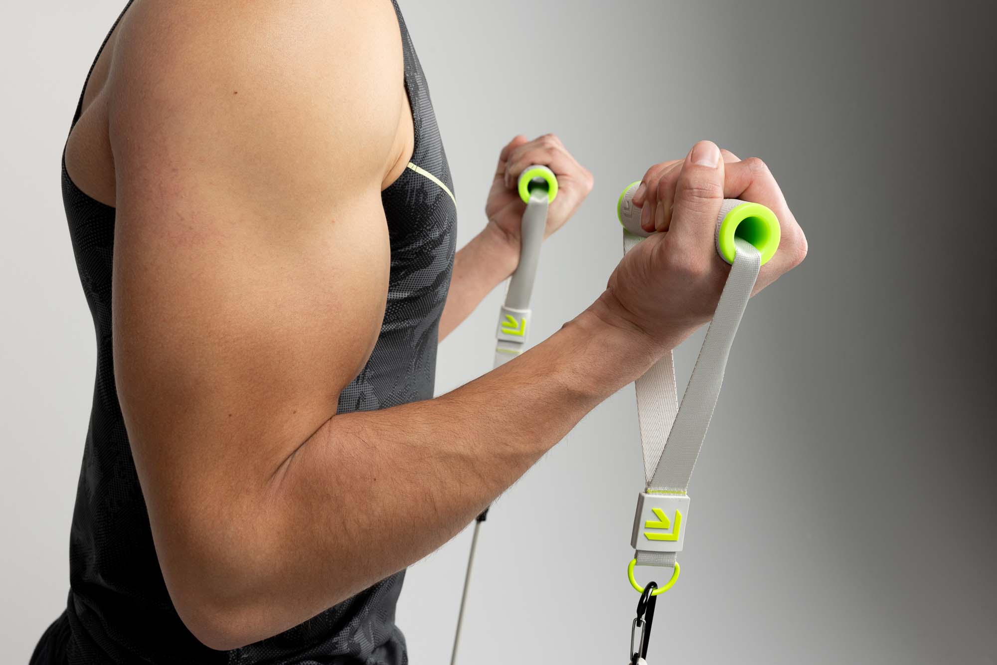 Close-up of a male model curling Rage Fitness resistance bands, biceps flexed in a Denver studio shoot