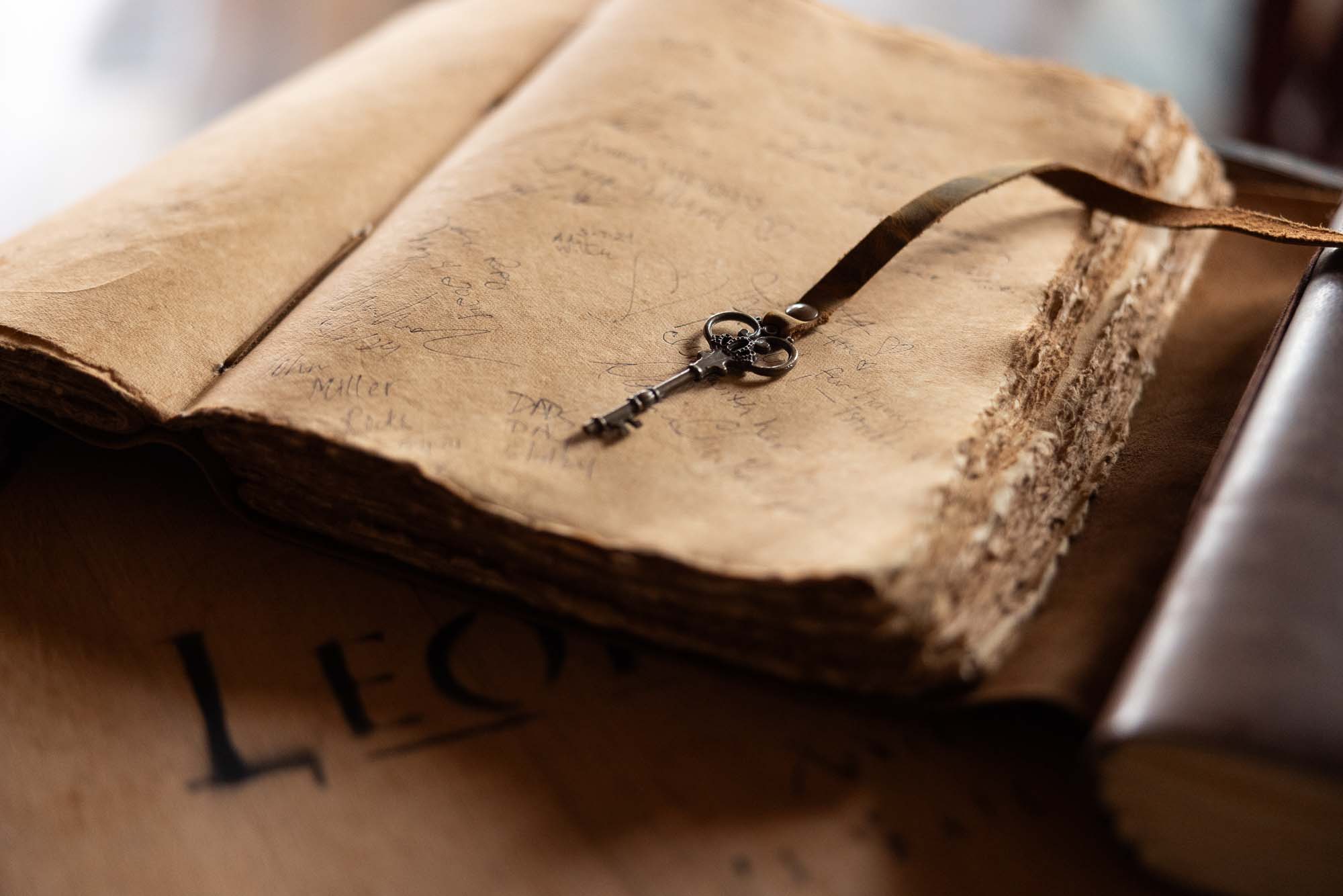 Detail photo of an antique skeleton key resting on the deckle-edged pages of the signed Leopold Brothers guestbook