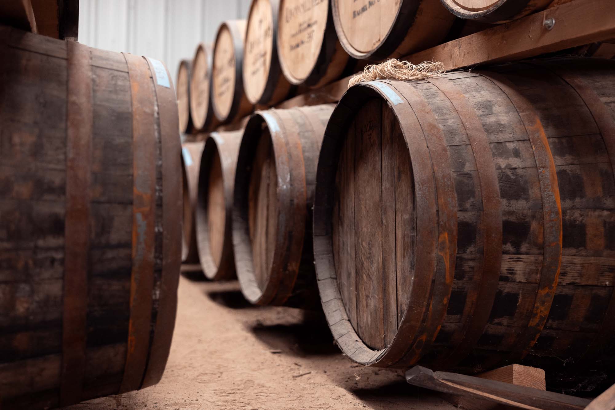 Row of well-aged Leopold Brothers whiskey barrels stacked on racks in the Denver distillery's aging warehouse