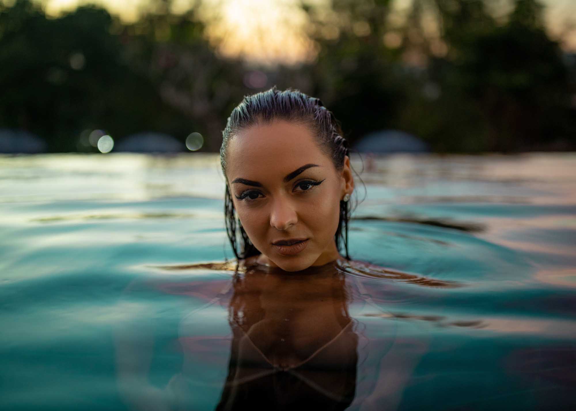 Fashion lifestyle portrait of a woman in a pool during golden hour while traveling in Asia.